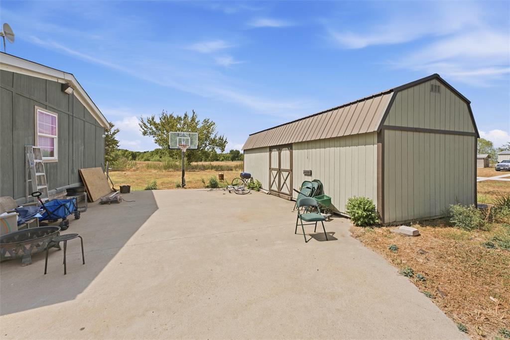 Concrete patio featuring a detached storage shed with a metal roof and a permanent basketball goal Concrete patio featuring a detached storage shed with a metal roof and a permanent basketball goal