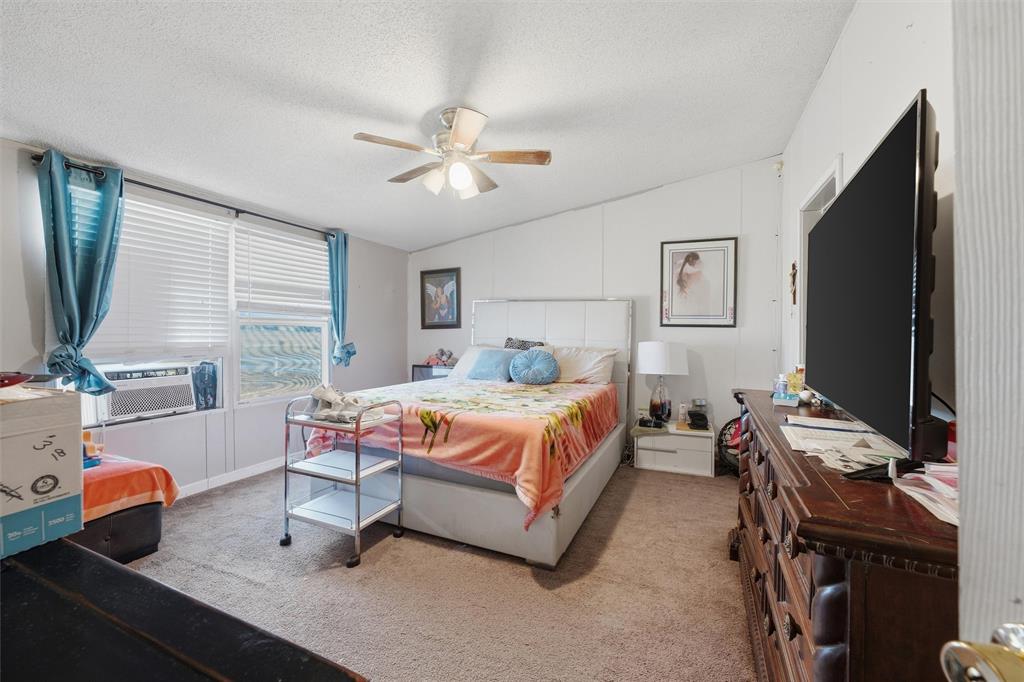 Bedroom with neutral wall paneling, carpeting, integrated ceiling fan with light fixture, and horizontal window blinds