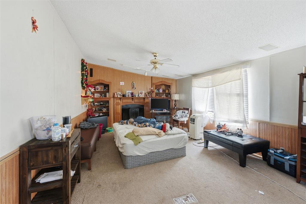 Living area featuring wood-paneled walls, built-in shelving, a central fireplace mantle, and a ceiling fan