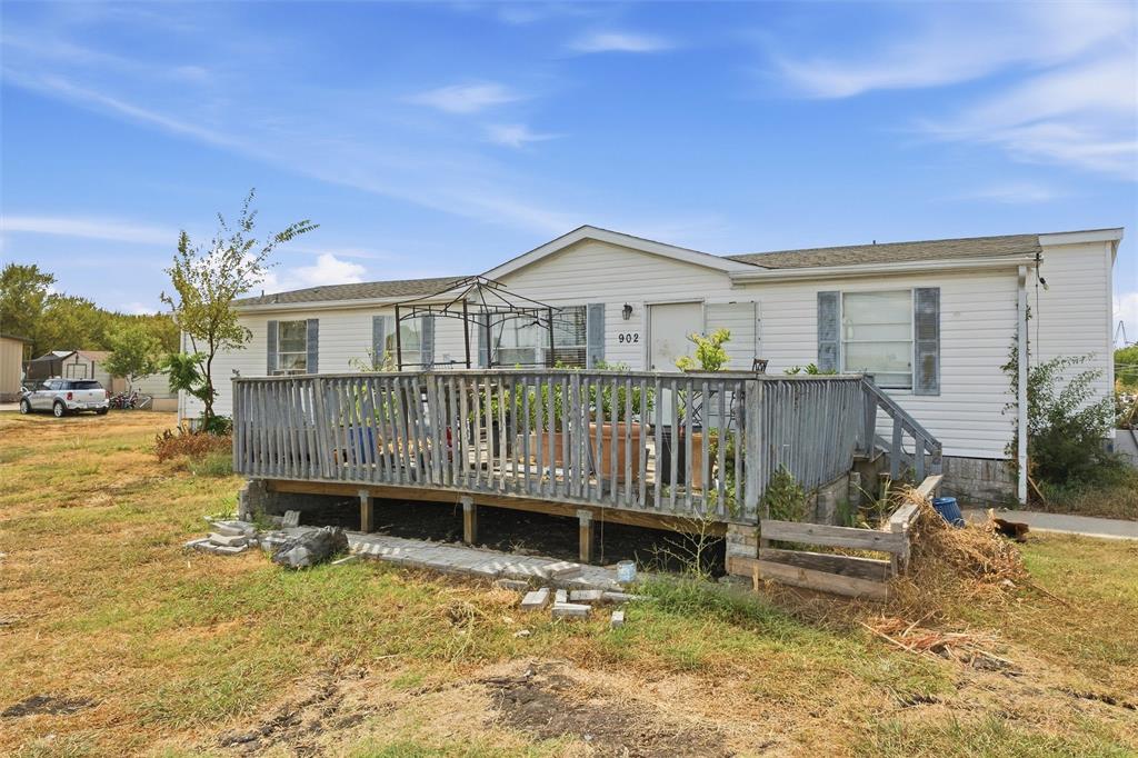 Single-story exterior featuring horizontal siding, a raised wood deck with balustrades, and window shutters Single-story exterior featuring horizontal siding, a raised wood deck with balustrades, and window shutters