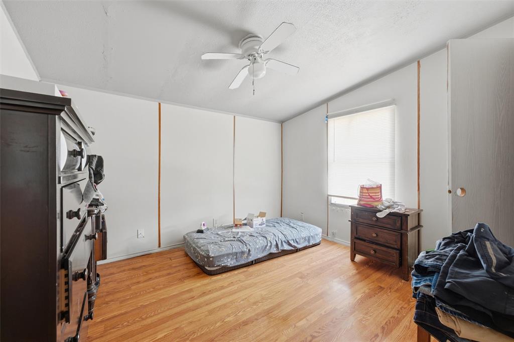 Interior room featuring wood-finish flooring, white paneled walls, and a white ceiling fan with integrated lighting
