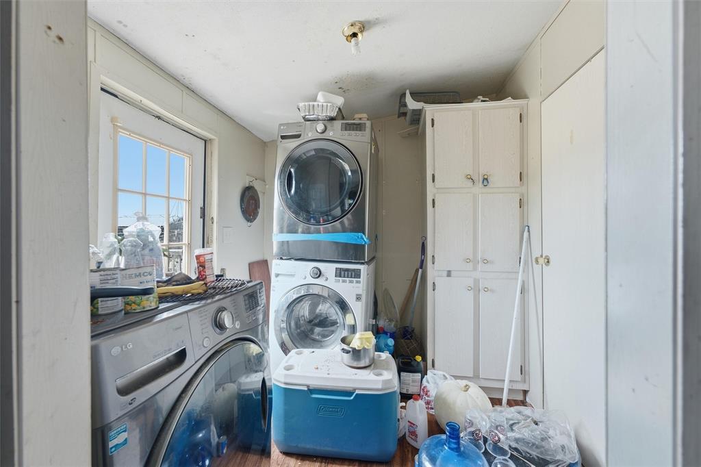 Utility area featuring built-in floor-to-ceiling cabinetry, a multi-pane exterior door, and stacked laundry appliances