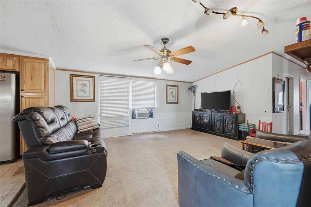 Living area featuring a vaulted ceiling, ceiling fan with light kit, multi-bulb track lighting, and window blinds Living area featuring a vaulted ceiling, ceiling fan with light kit, multi-bulb track lighting, and window blinds