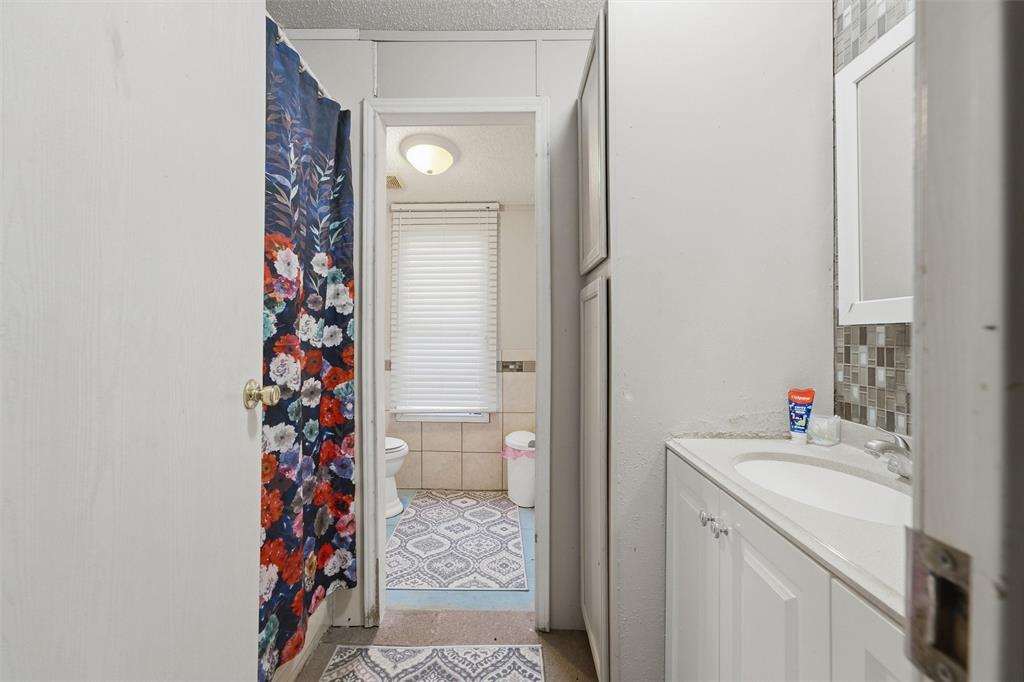 Bathroom featuring a white vanity cabinet with an integrated sink and tiled backsplash, complemented by full-height built-in storage cabinetry