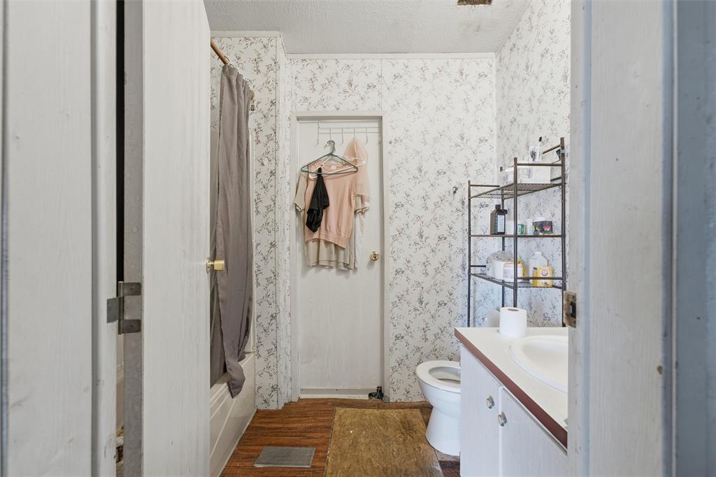 Bathroom featuring a white vanity cabinet, a drop-in sink, a shower and tub combination, and wood-finish flooring