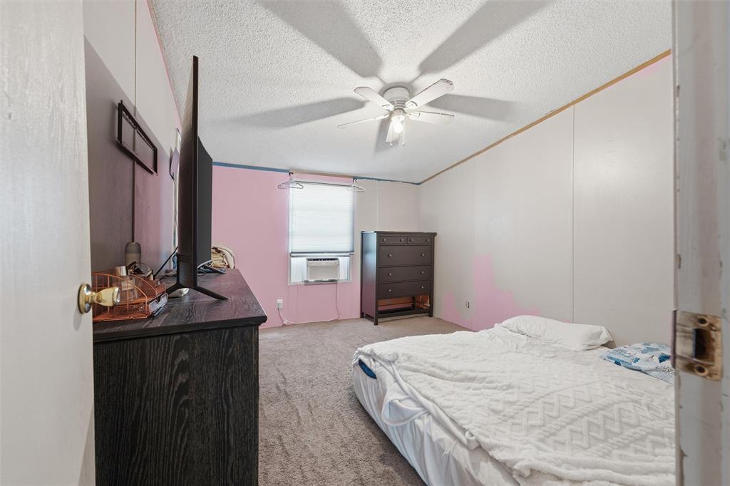 Room featuring wall-to-wall carpeting, a ceiling-mounted fan with integrated lighting, and a window with a mounted window air conditioning unit