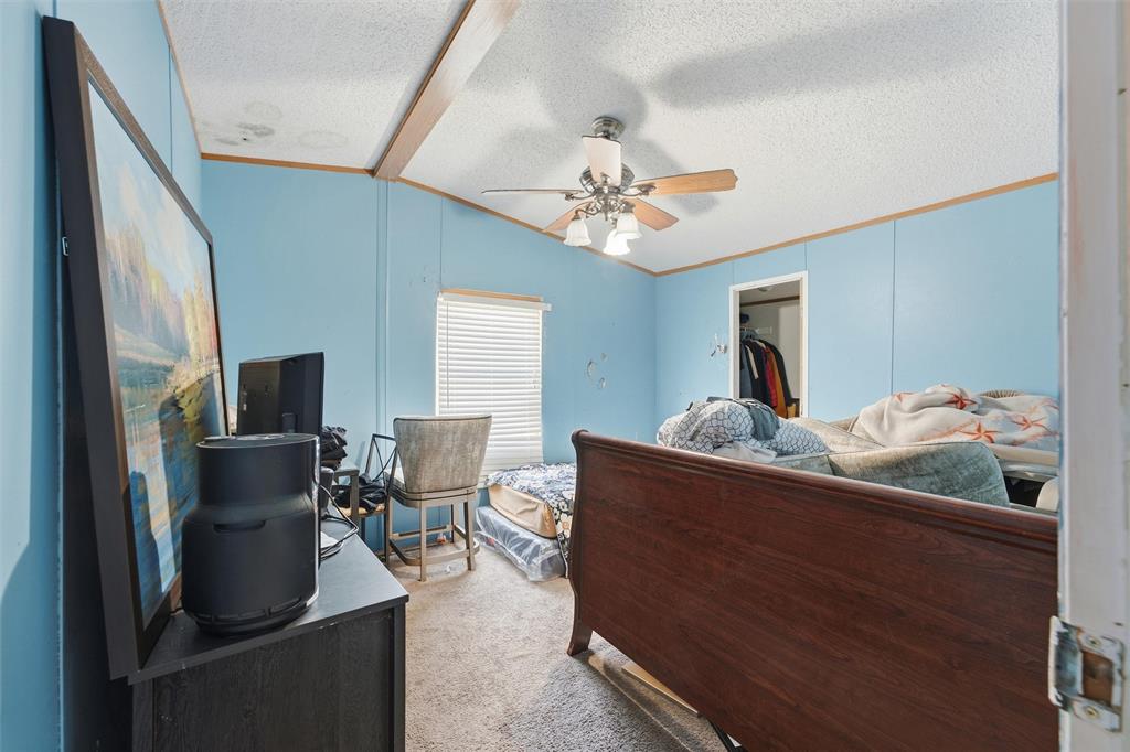Vaulted ceiling featuring a central support beam and a multi-light ceiling fan with wood-tone blades, paired with horizontal window blinds