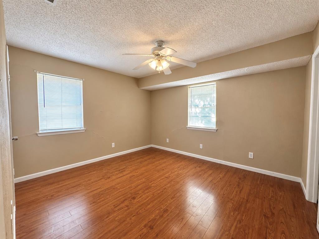 Wood-finish flooring, two windows with integrated blinds, and a ceiling-mounted light fixture with fan