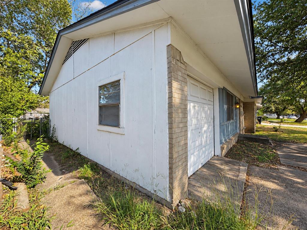 Exterior view featuring white panel siding, brick masonry accent, single-car garage door, and concrete driveway