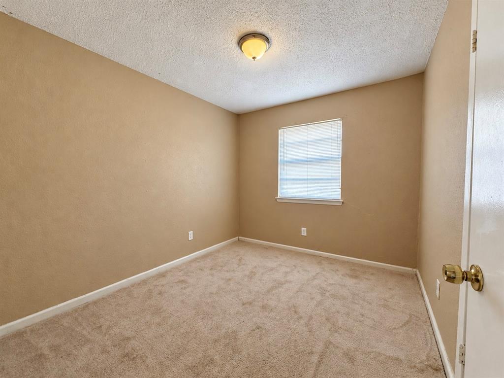Neutral wall-to-wall carpeting, textured ceiling finish, single-window illumination, and a flush-mount dome light fixture