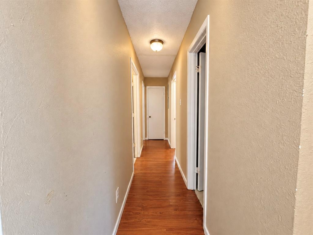 Hallway featuring wood-finish flooring, textured walls, and a flush-mount ceiling light fixture