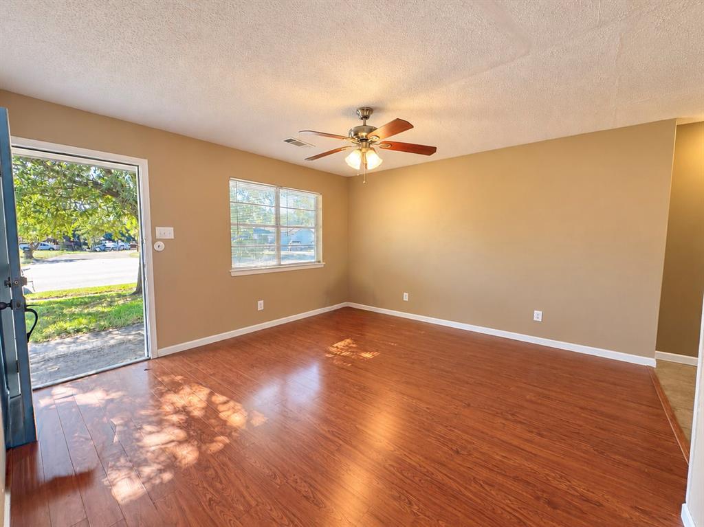 Wood-finish flooring, central ceiling fan with integrated lighting, and a single-pane window