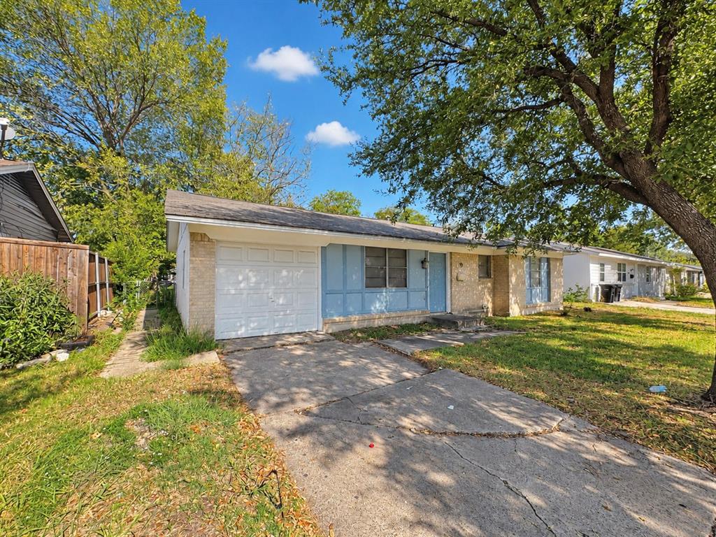 Single-story exterior featuring a brick facade, attached one-car garage, concrete driveway, and mature landscaping