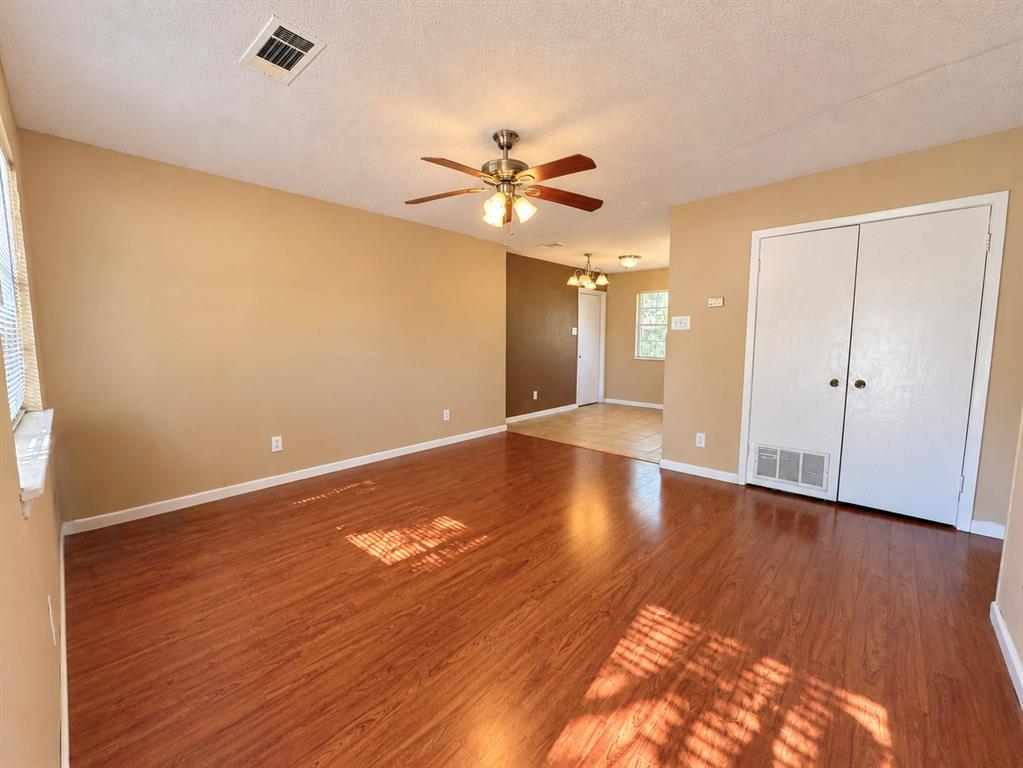 Interior room featuring wood-finish flooring, a ceiling-mounted light fixture with a central fan, and double-door closet cabinetry