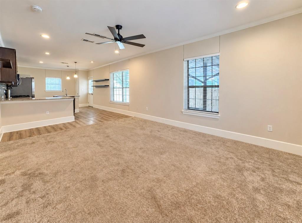 Open floor plan featuring neutral carpeting, recessed lighting, a modern ceiling fan, wood-finish flooring, and multi-pane windows