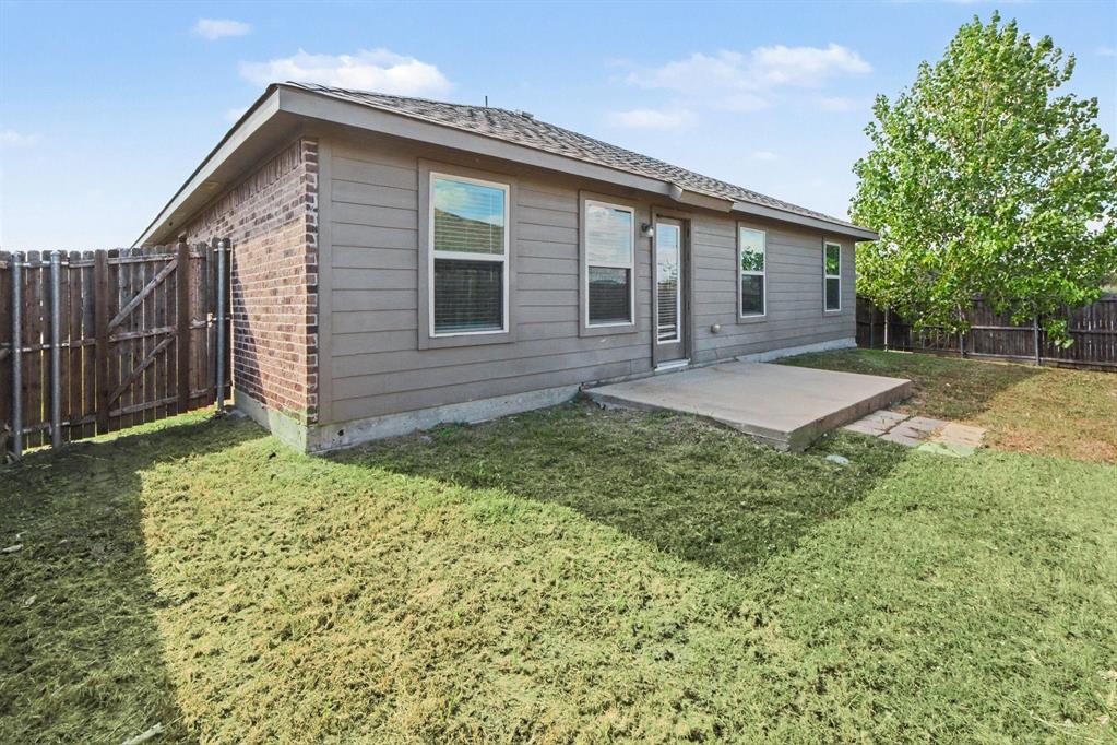 Rear exterior featuring brick and horizontal siding, concrete patio, and wood privacy fencing