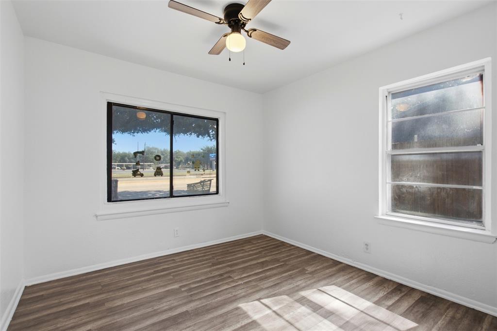 Interior space featuring wood-finish flooring, two windows, and a ceiling fan with integrated light fixture
