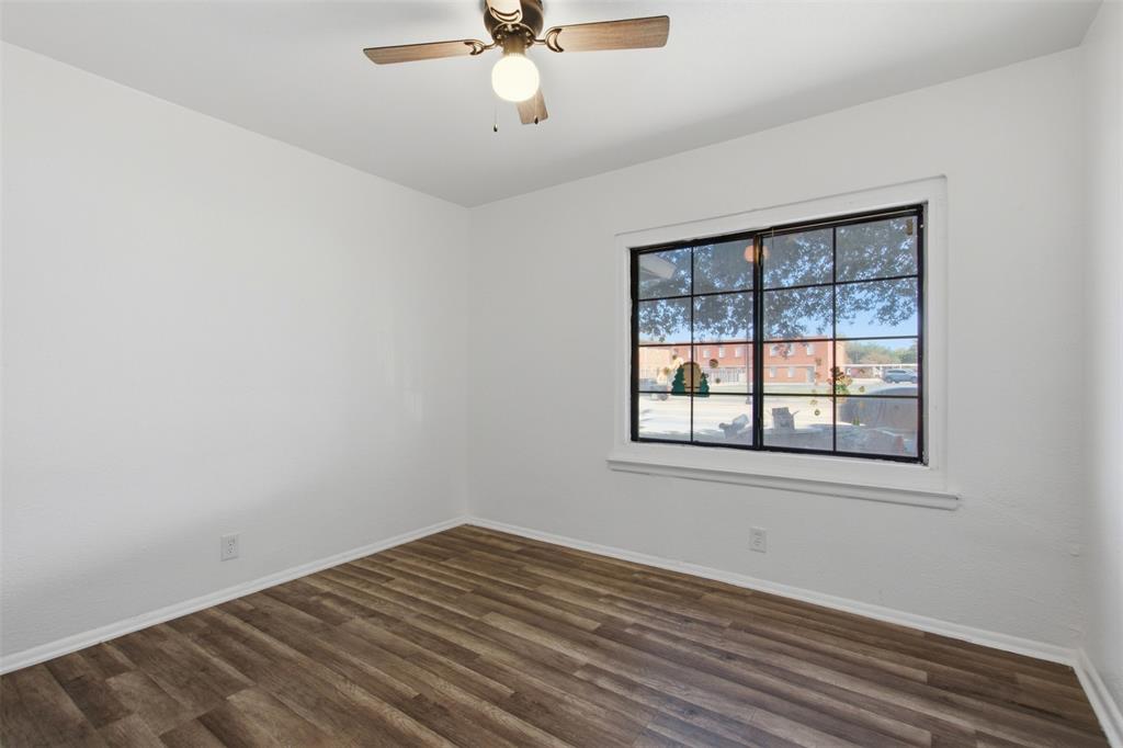 Neutral-toned interior featuring wood-finish flooring, a multi-pane grid window with a dark frame, and a ceiling fan with integrated lighting
