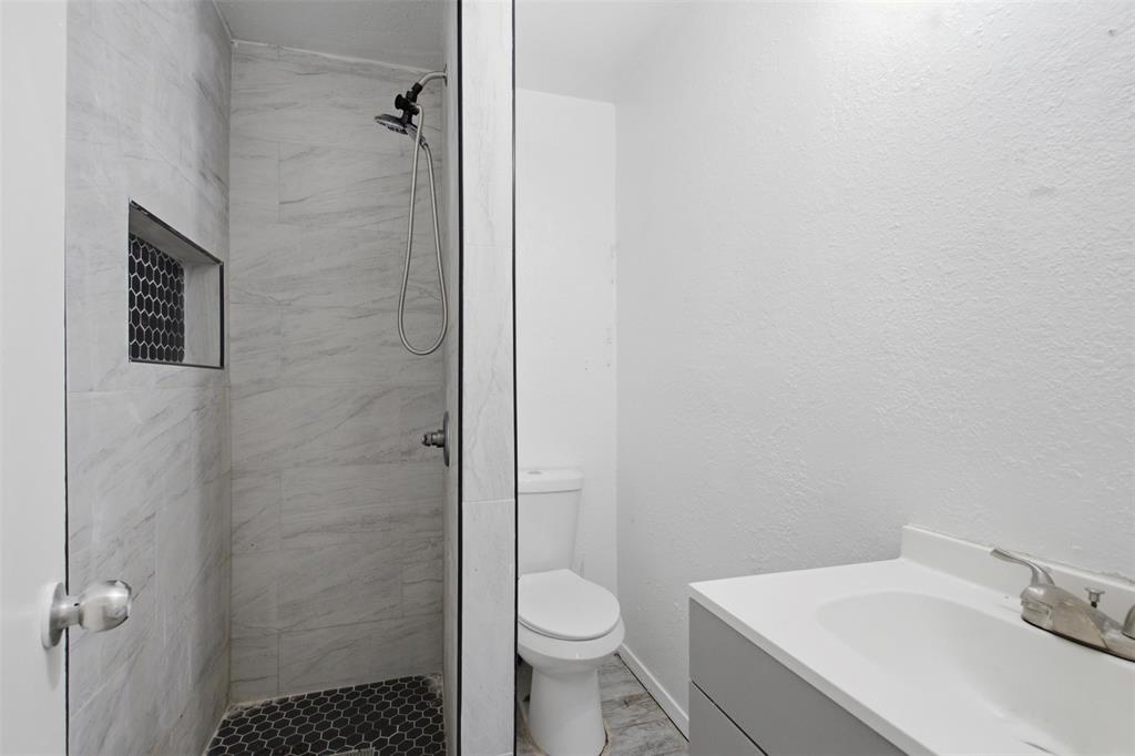 Bathroom featuring a walk-in shower with light-toned wall tile, a dark-toned hexagonal tile floor, and a built-in recessed niche
