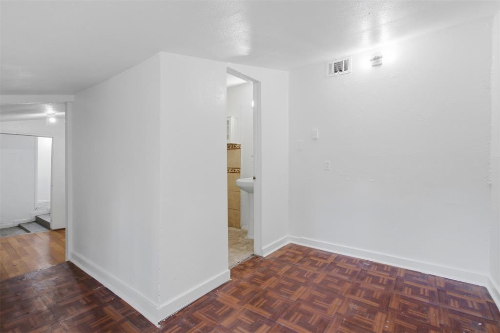 Interior space featuring parquet wood-finish flooring, smooth white walls, and a built-in pedestal sink
