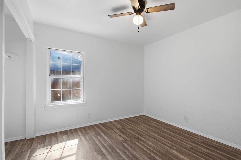 Wood-finish flooring, single-hung window with decorative muntins, and a ceiling-mounted light fixture with fan blades