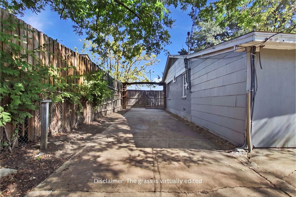 Concrete driveway with a fenced perimeter and wooden gate