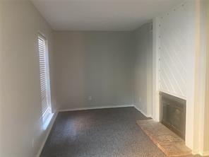 Unfurnished living room featuring a glass covered fireplace and dark colored carpet