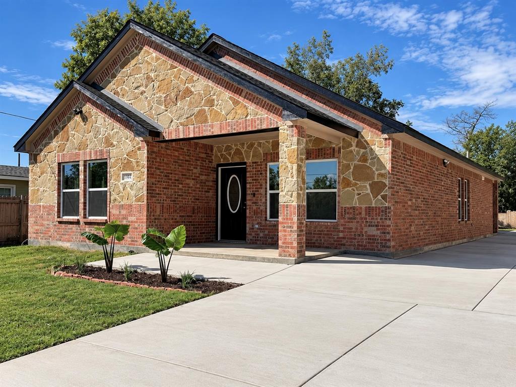 Exterior facade featuring a brick and stone veneer, gable roofline, covered front porch, and concrete driveway