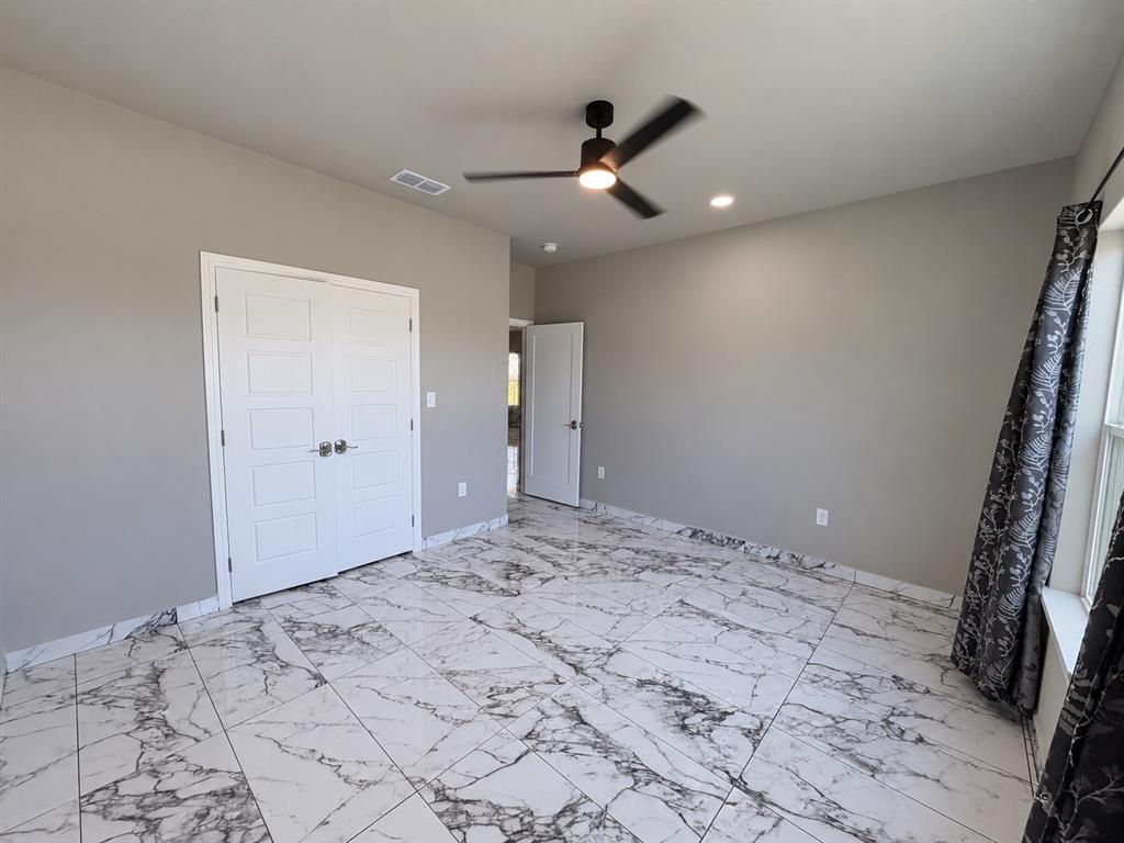 Room featuring large-format tile flooring with a marble-finish pattern, double-door closet, recessed lighting, and a modern matte-finish ceiling fan