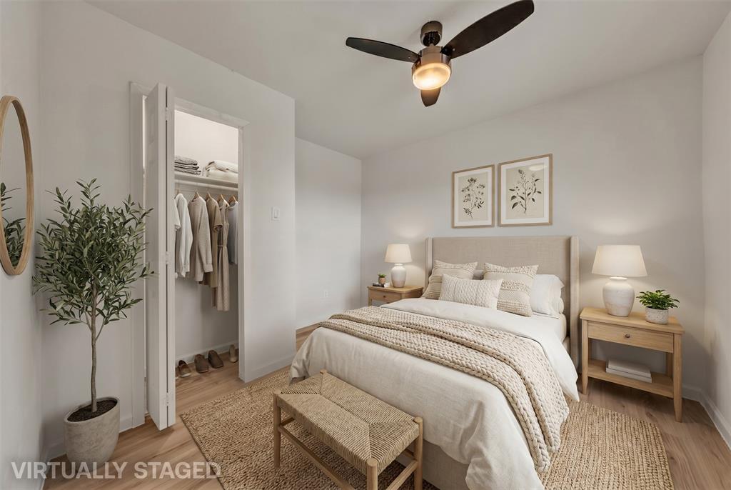 Bedroom featuring wood-finish flooring, a ceiling fan with integrated lighting, and a reach-in closet with built-in shelving
