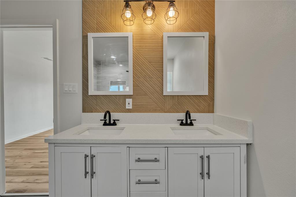 Double vanity with white cabinetry, quartz countertop, dual rectangular undermount sinks, geometric tile backsplash, and matte black fixtures