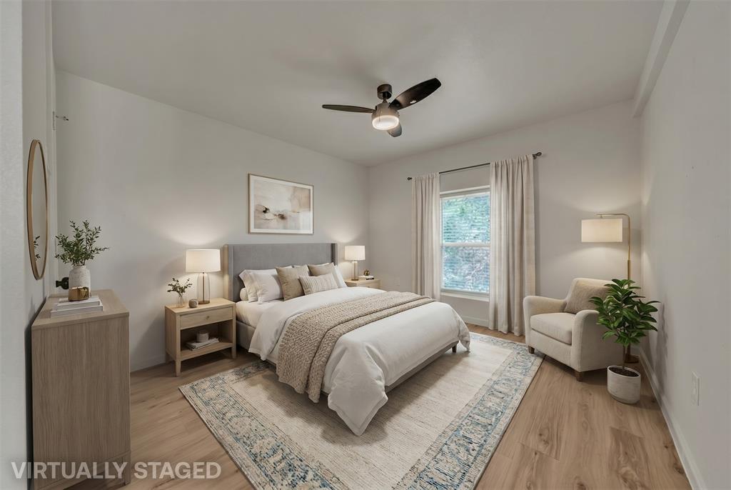 Room featuring wood-finish flooring, a neutral color palette, and a multi-blade ceiling fan with integrated lighting