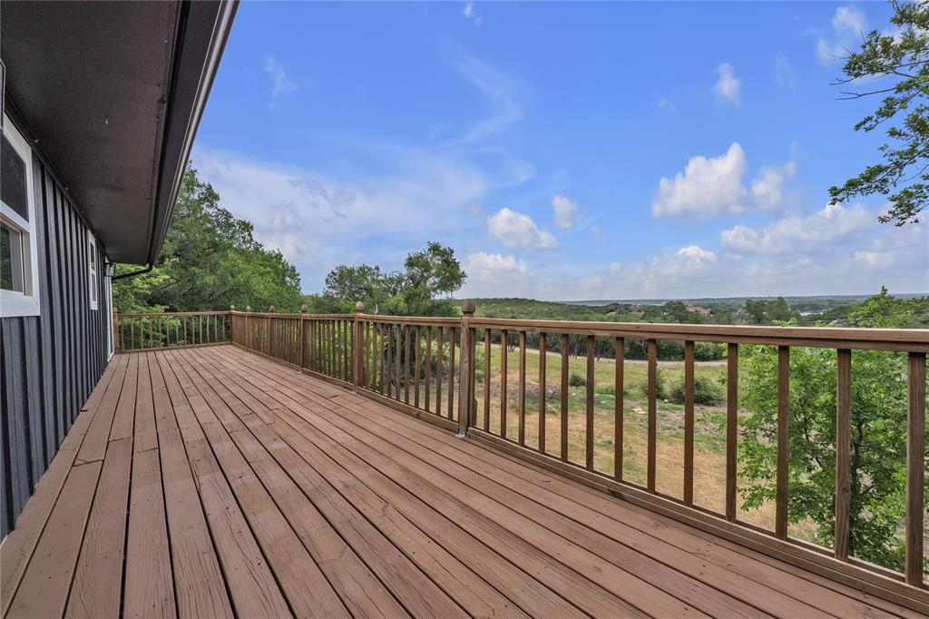 Expansive wood deck featuring vertical wood balusters and a post-and-rail railing system, complemented by extensive natural landscape scenery