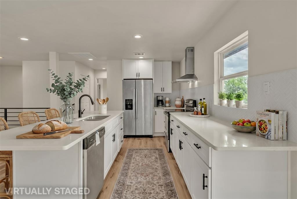Kitchen featuring white cabinetry, solid-surface countertops, stainless steel appliances, a range hood, and wood-finish flooring Kitchen featuring white cabinetry, solid-surface countertops, stainless steel appliances, a range hood, and wood-finish flooring
