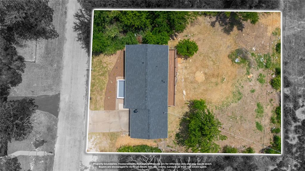 Aerial perspective of property featuring an expansive lot, mature trees, a roof with shingle finish, a concrete driveway, and an elevated wood deck