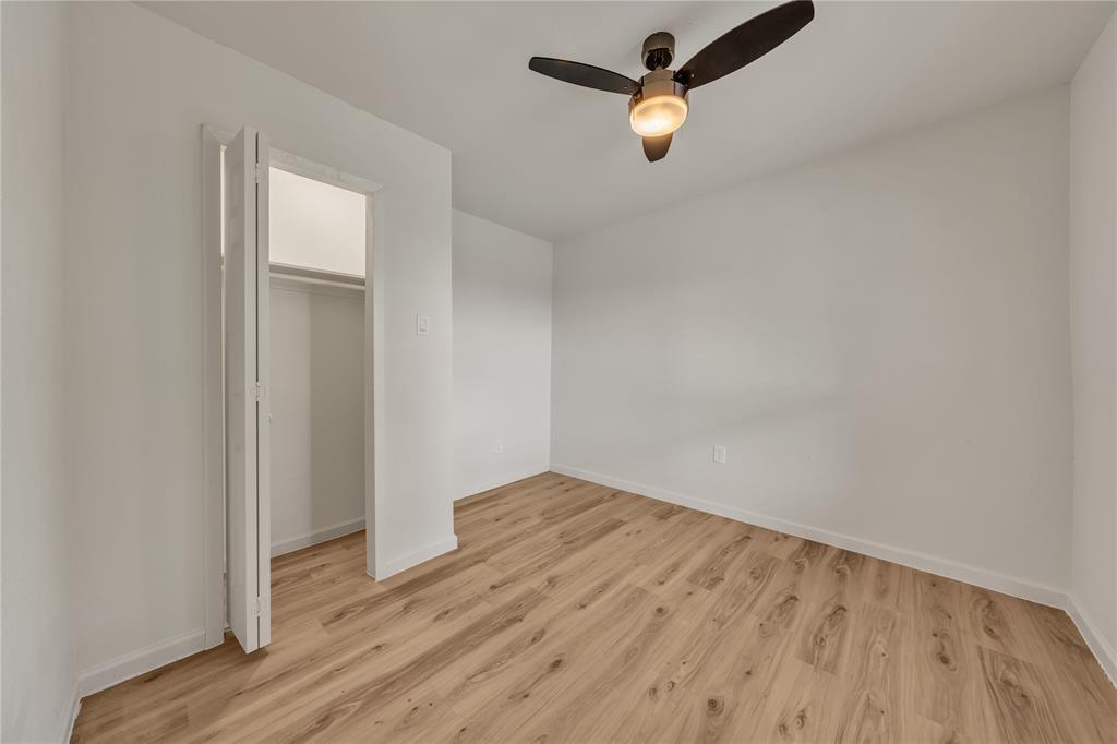 Interior room featuring wood-finish flooring, a bi-fold closet, and a multi-blade ceiling fan with integrated lighting