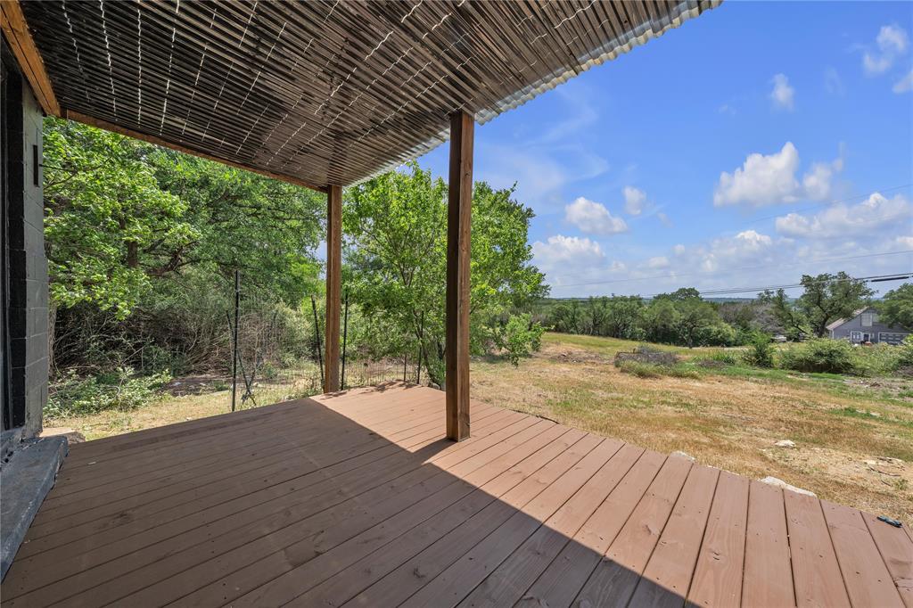 Covered deck featuring wood-finish decking, timber support posts, and a corrugated overhead canopy