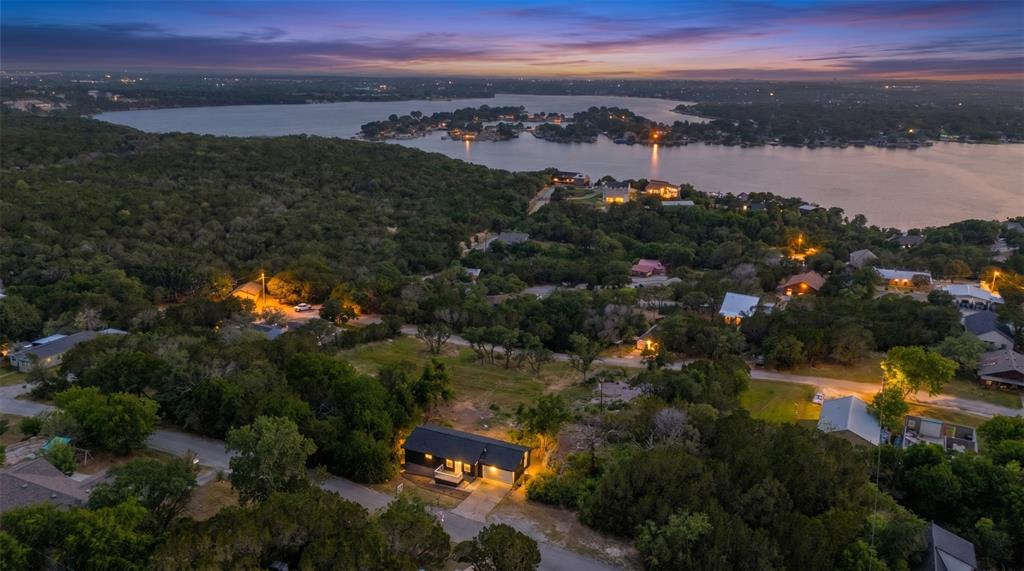 Aerial perspective of a single-story residence situated on a treed lot with proximity to a large lake Aerial perspective of a single-story residence situated on a treed lot with proximity to a large lake