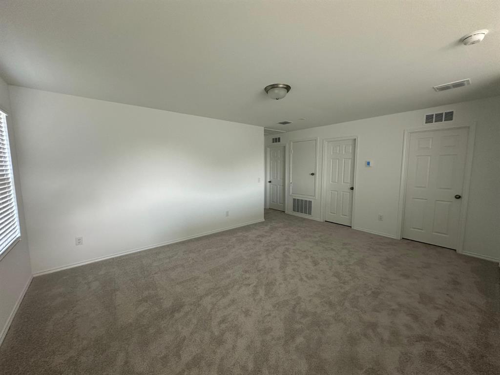 Neutral-toned wall-to-wall carpeting, white interior walls, and multiple paneled doors