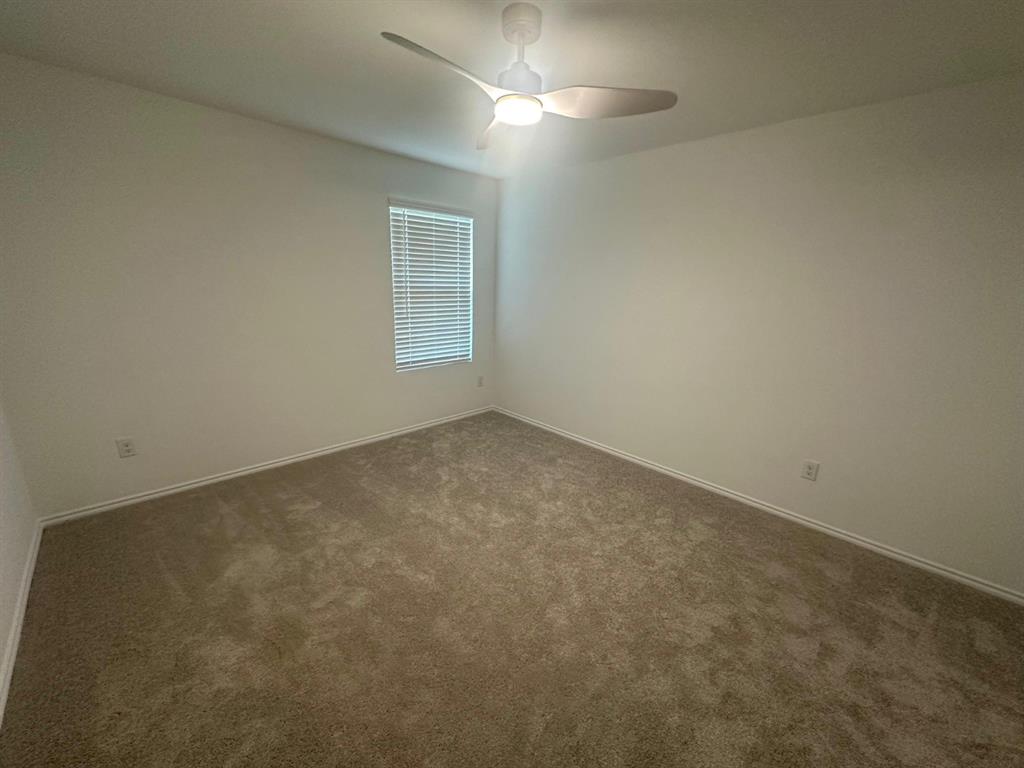 Room featuring neutral-toned carpeting, a modern ceiling fan with integrated lighting, and a window equipped with horizontal blinds Room featuring neutral-toned carpeting, a modern ceiling fan with integrated lighting, and a window equipped with horizontal blinds