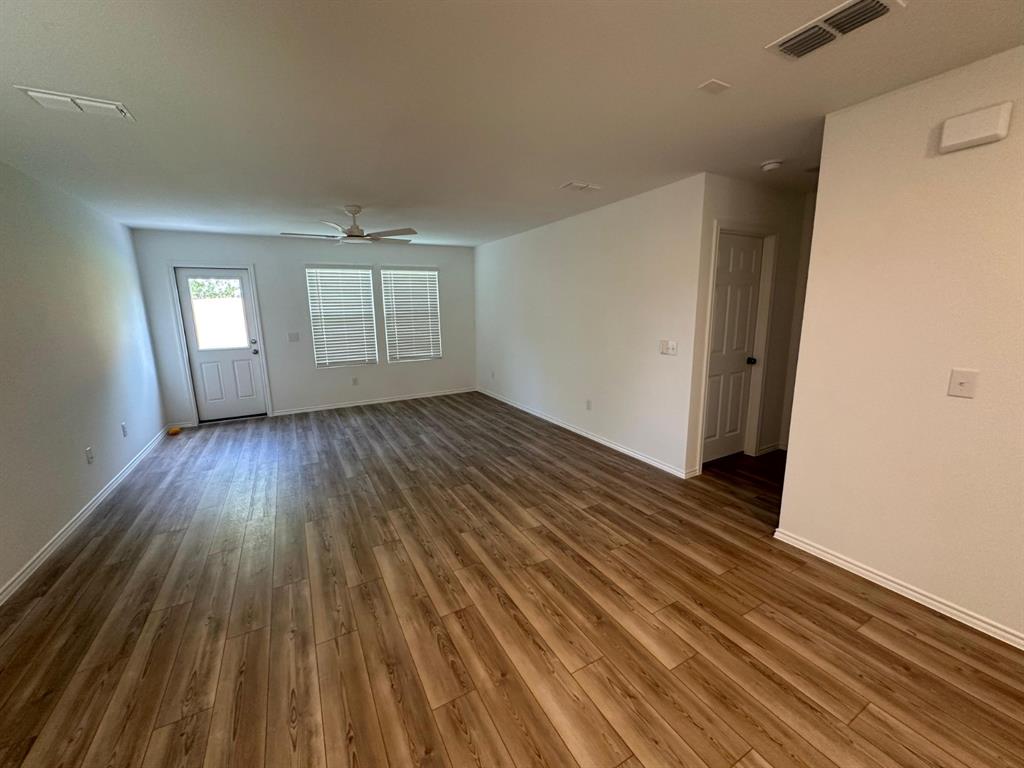 Interior space featuring wood-finish flooring, a ceiling fan, a multi-pane exterior door, and neutral wall tones