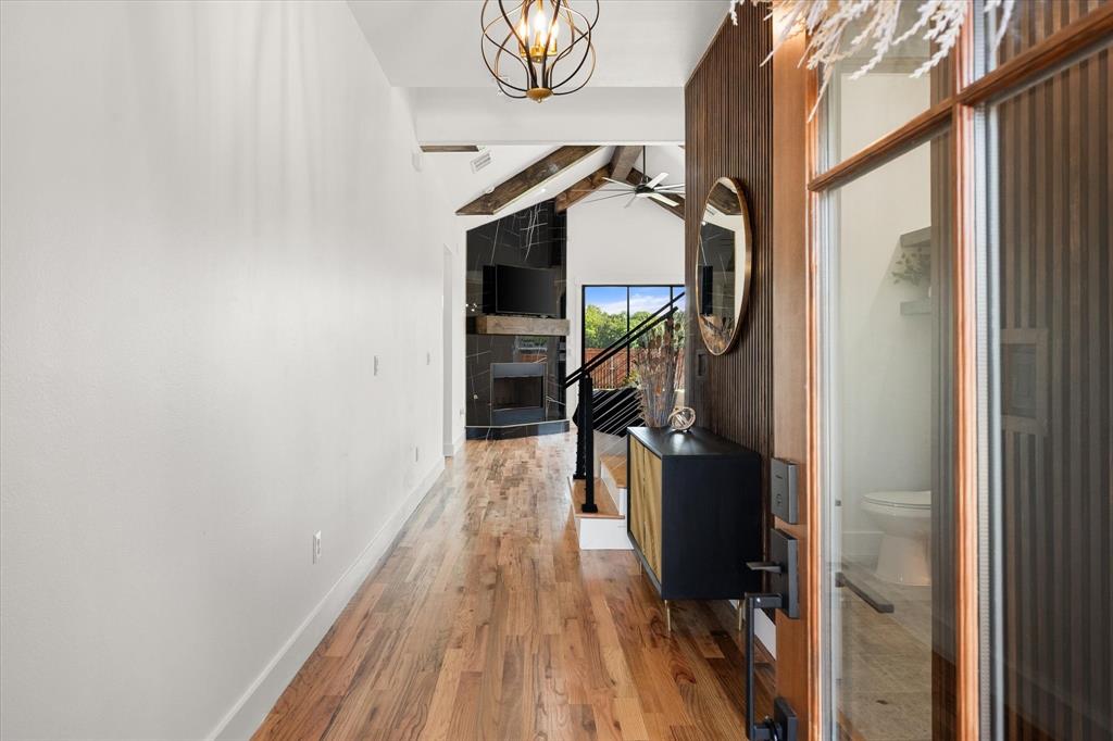 Entryway featuring oak wood flooring, vaulted ceilings with wood beams, a fireplace with black tile ......