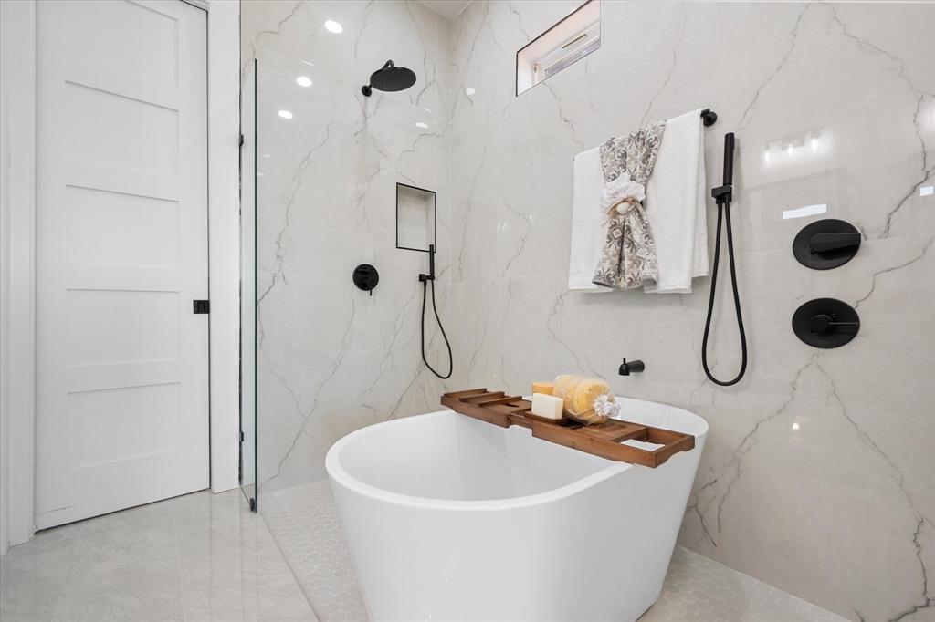 Primary bathroom 1- ensuite bathroom with a wet area that includes dual rainfall shower heads, a freestanding soaking tub with matte black hardware, floor-to-ceiling tile wall, glass-enclosed shower, built-in recessed niches