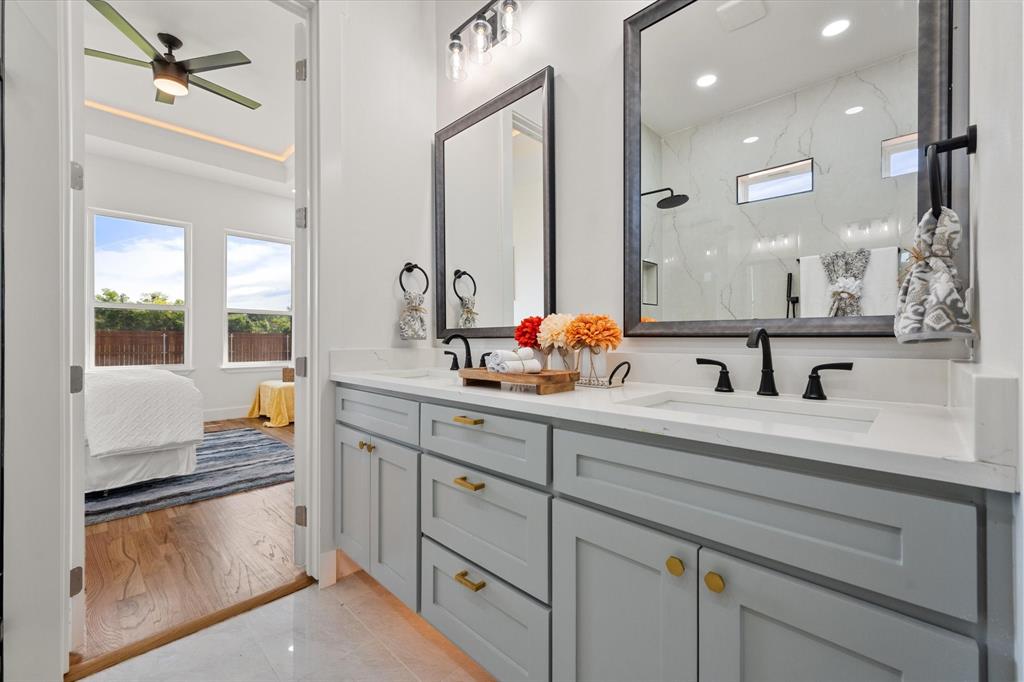 Dual-sink vanity with quartz countertops, matte black plumbing fixtures, and framed mirrors