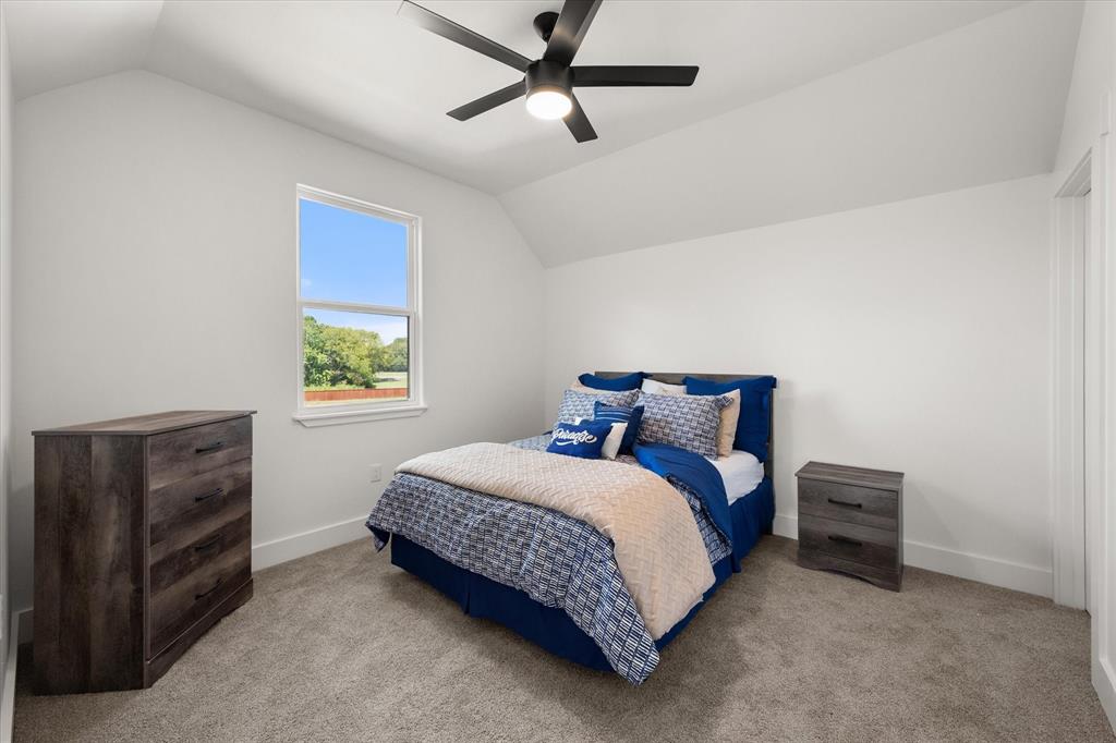 Vaulted ceiling featuring a matte black finish ceiling fan and neutral wall-to-wall carpeting