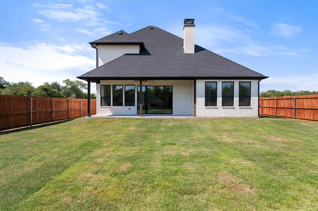 Rear view of the home with spacious backyad and stained fence