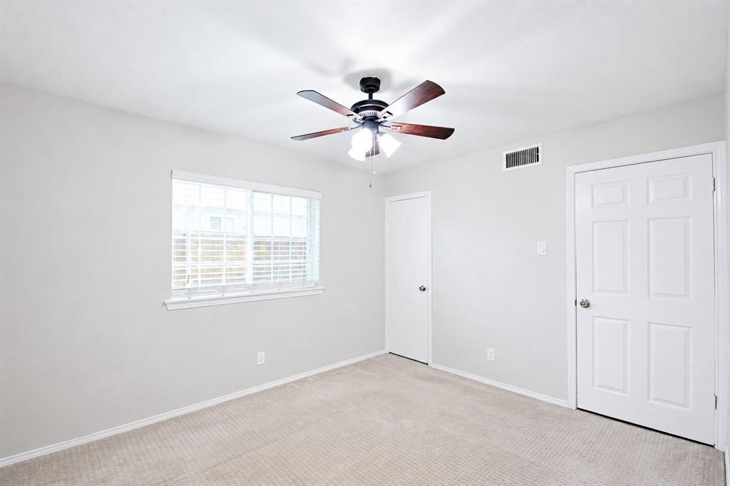 Neutral-toned interior featuring wall-to-wall carpeting, a multi-pane window with blinds, a ceiling fan with integrated lighting, and two six-panel interior doors