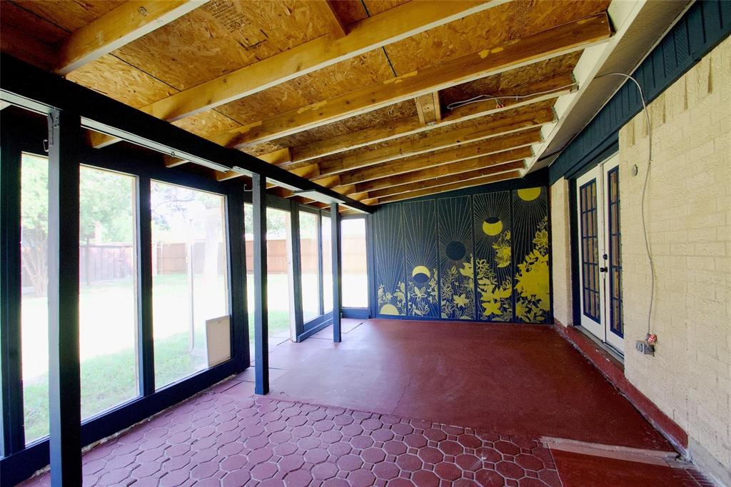 Enclosed sunroom featuring a covered porch with exposed wood beams, red hexagonal tile flooring, expansive floor-to-ceiling windows, and French doors