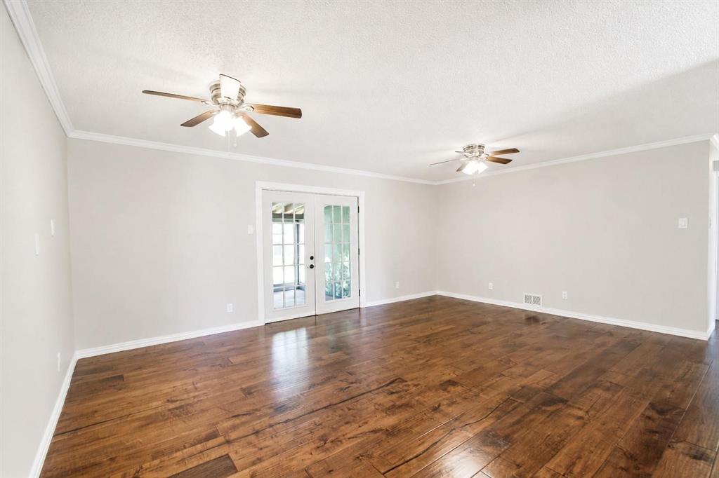 Spacious room featuring wood-finish flooring, dual ceiling fans, and French doors
