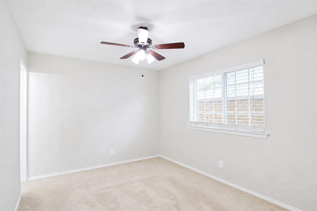 Neutral-toned carpeted flooring, wall-mounted ceiling fan with integrated lighting, and horizontal window blinds
